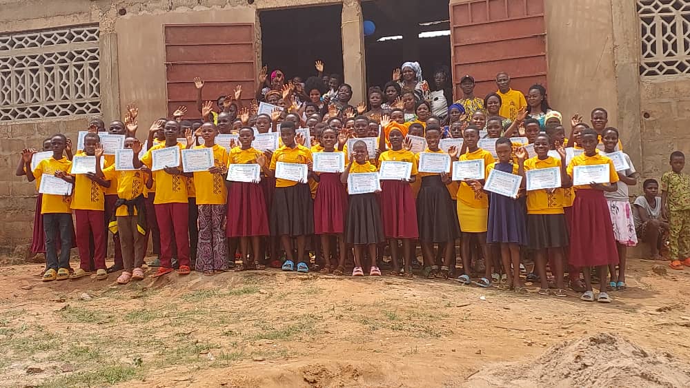 Des enfants présentent fièrement leur attestation devant le centre
